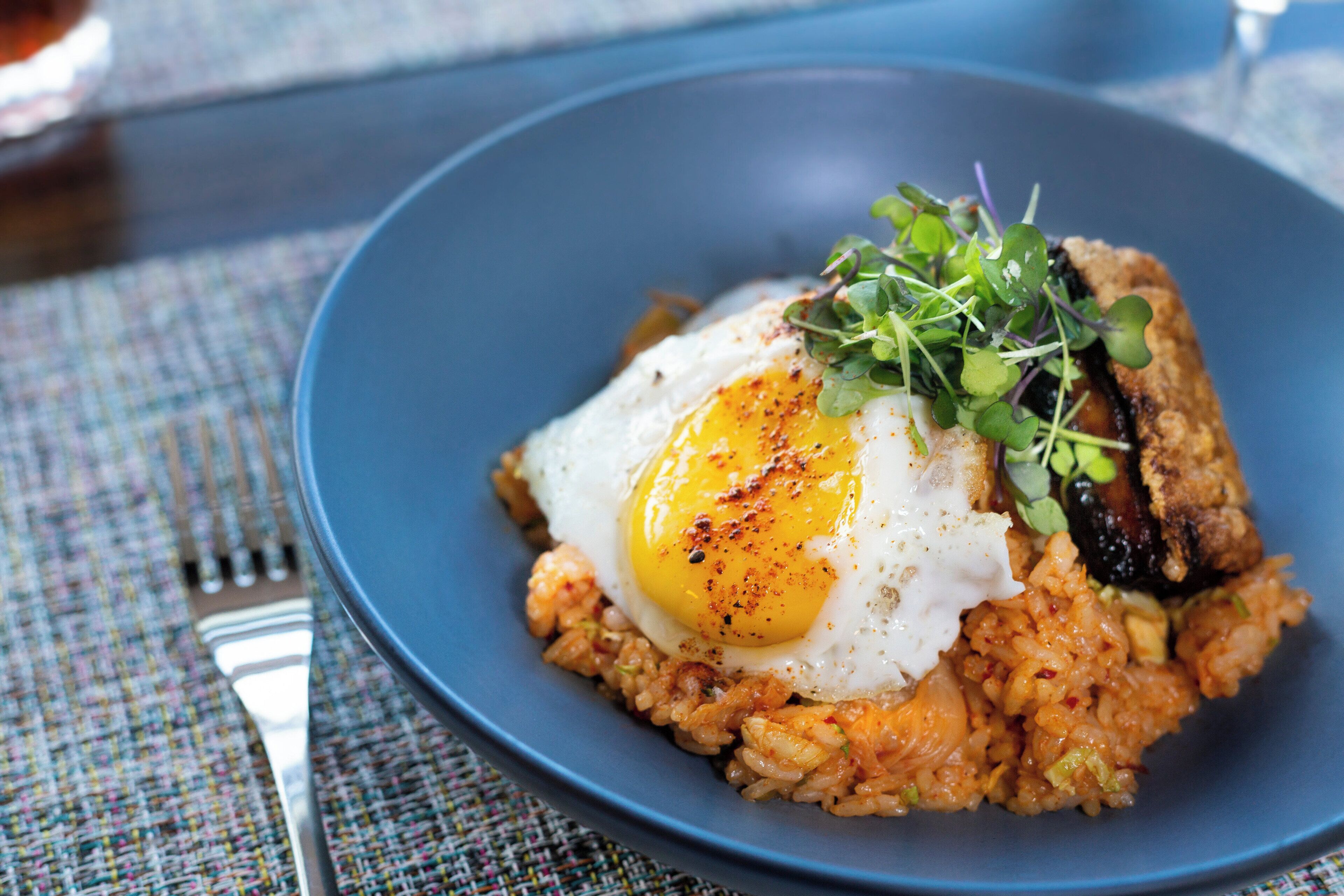 A plate with a fried egg, greens, and a side of rice.