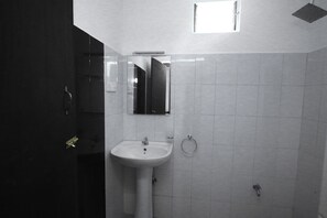 Un baño con lavamanos blanco, un espejo y un aro para toallas.