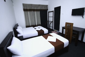 Habitación de hotel con dos camas, un escritorio, una silla, un televisor y una ventana con cortinas.