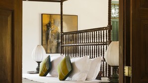 A four-poster bed with white linens and green and yellow pillows, a wooden floor, and a painting on the wall. - The Last House (Morakatiyara)