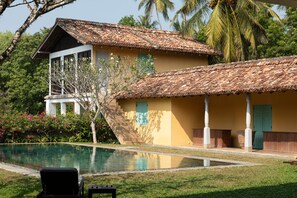 A two-story building with a tiled roof, a swimming pool, and a staircase leading to the upper floor.