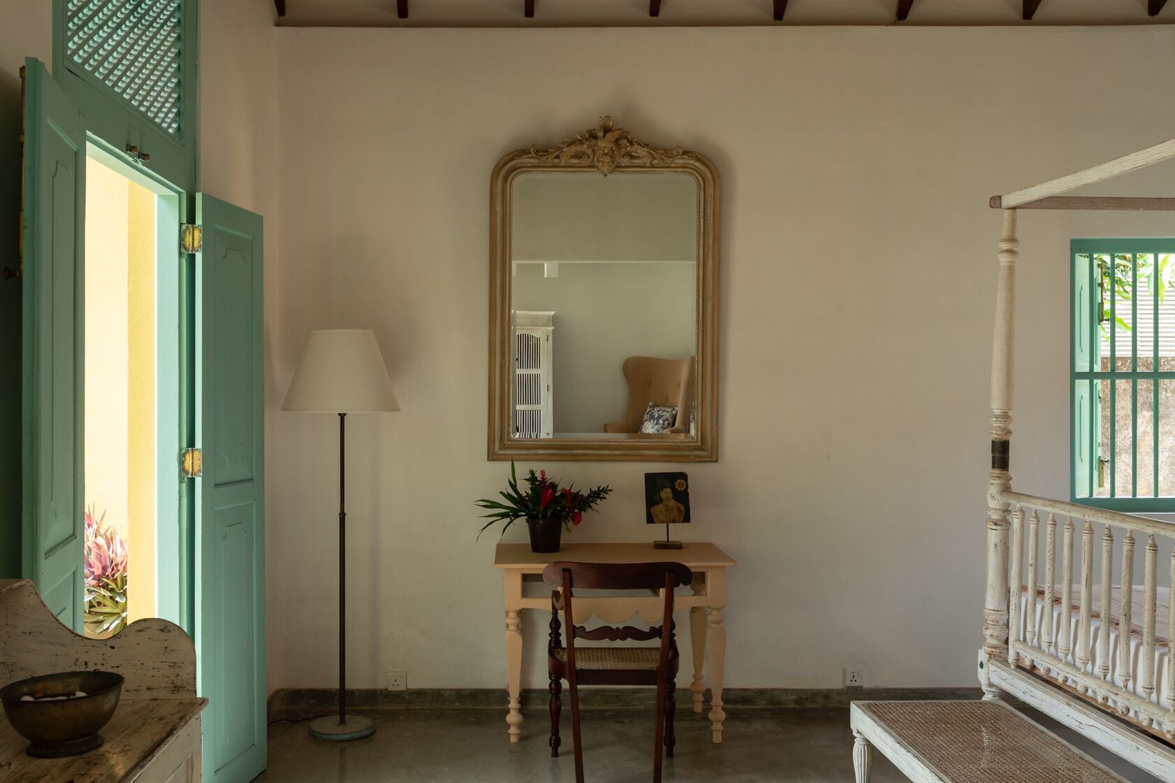 A room with a wooden desk, a mirror, a lamp, and a chair.