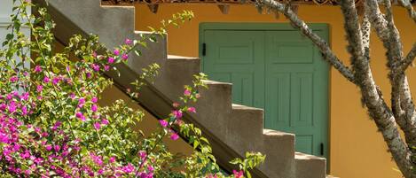 A building with a tiled roof, a green door, and pink flowers in the foreground.