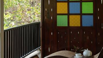 A wooden bench with woven seats and a table with a teapot and cup, set against a wooden partition with a grid of colored panels.