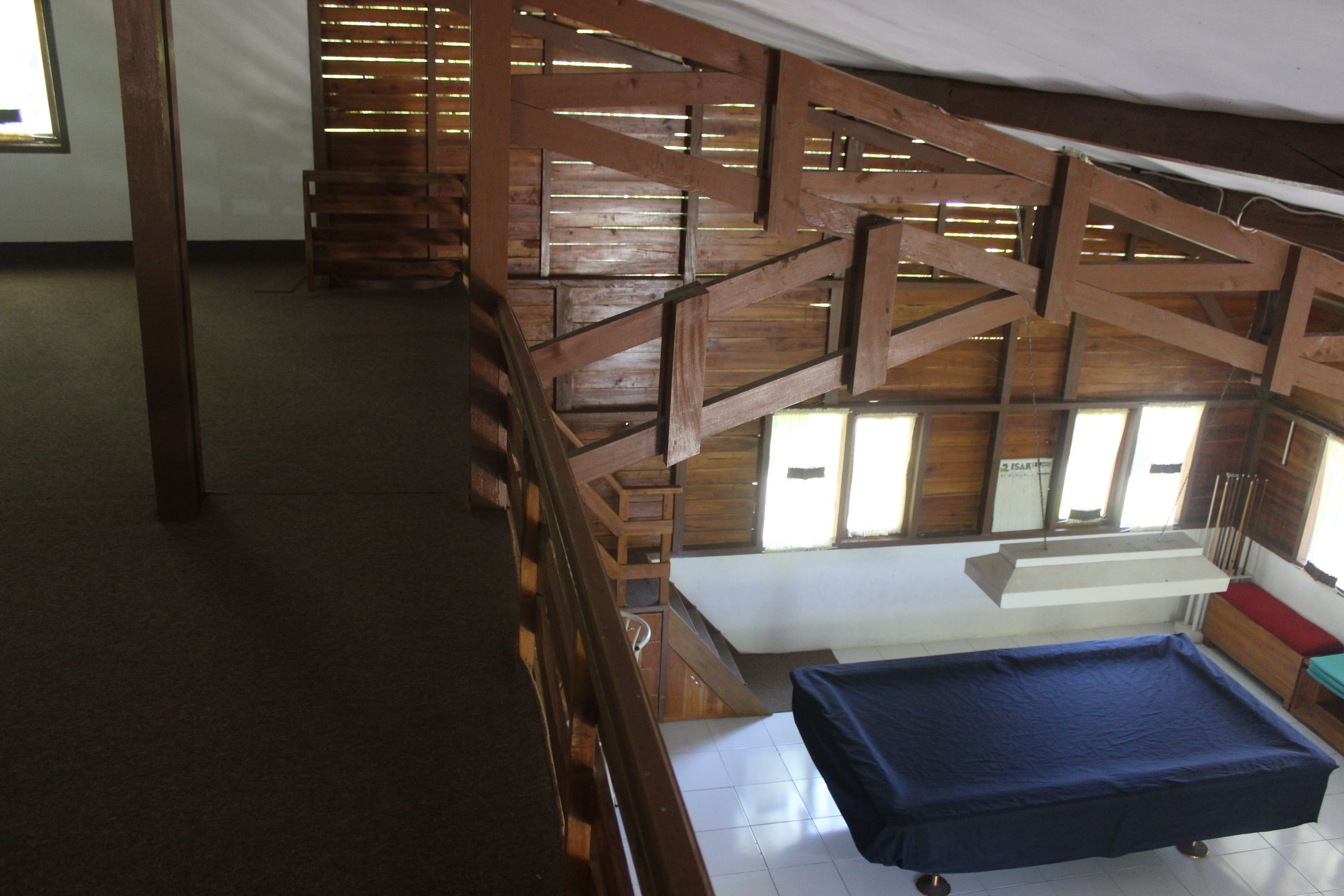 A room with a wooden staircase, a pool table, and a window with blinds.