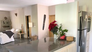 Een moderne keuken met een roestvrijstalen koelkast, een aanrecht en een eethoek met een witte tafel en stoelen.