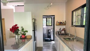 Een moderne keuken met een centraal eiland, roestvrijstalen apparatuur en uitzicht op een balkon.