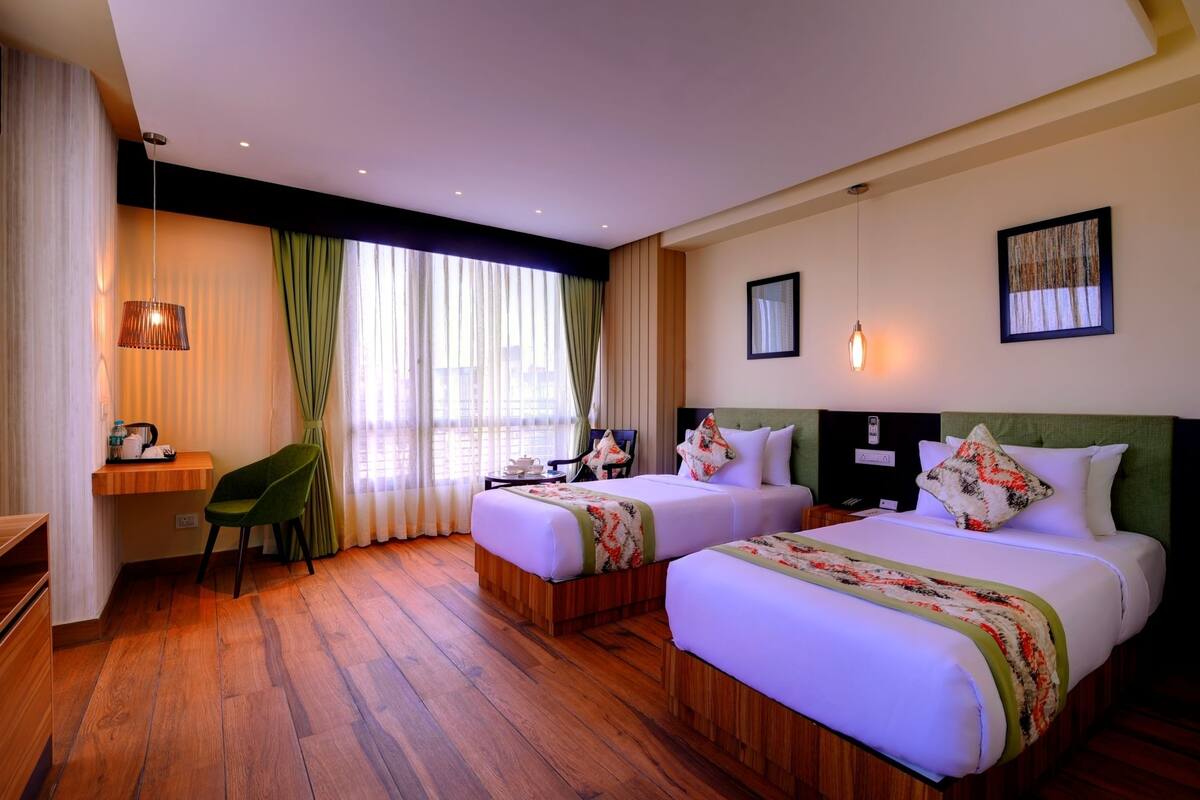 Habitación de hotel con dos camas, un escritorio y una silla.