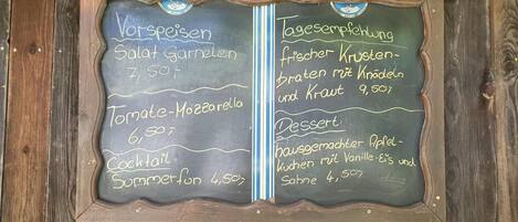 Una pizarra con menú de comida y bebidas, e precios.
