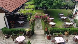 A courtyard with outdoor seating, a stone pathway, and greenery. - Landgasthof Zum Kirchenwirt (Thyrnau)
