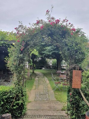 A garden pathway leading to a rustic wooden structure with a signboard. - Landgasthof Zum Kirchenwirt (Thyrnau)