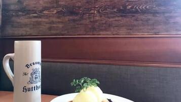 Una pared de madera con un cuadro enmarcado y un adorno. Sobre una mesa, una taza blanca con texto y un plato con comida.