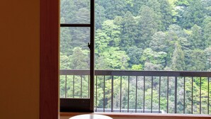 A room with a balcony overlooking a forested area.