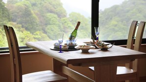 A dining table with chairs, a bottle of champagne, and a glass of water.