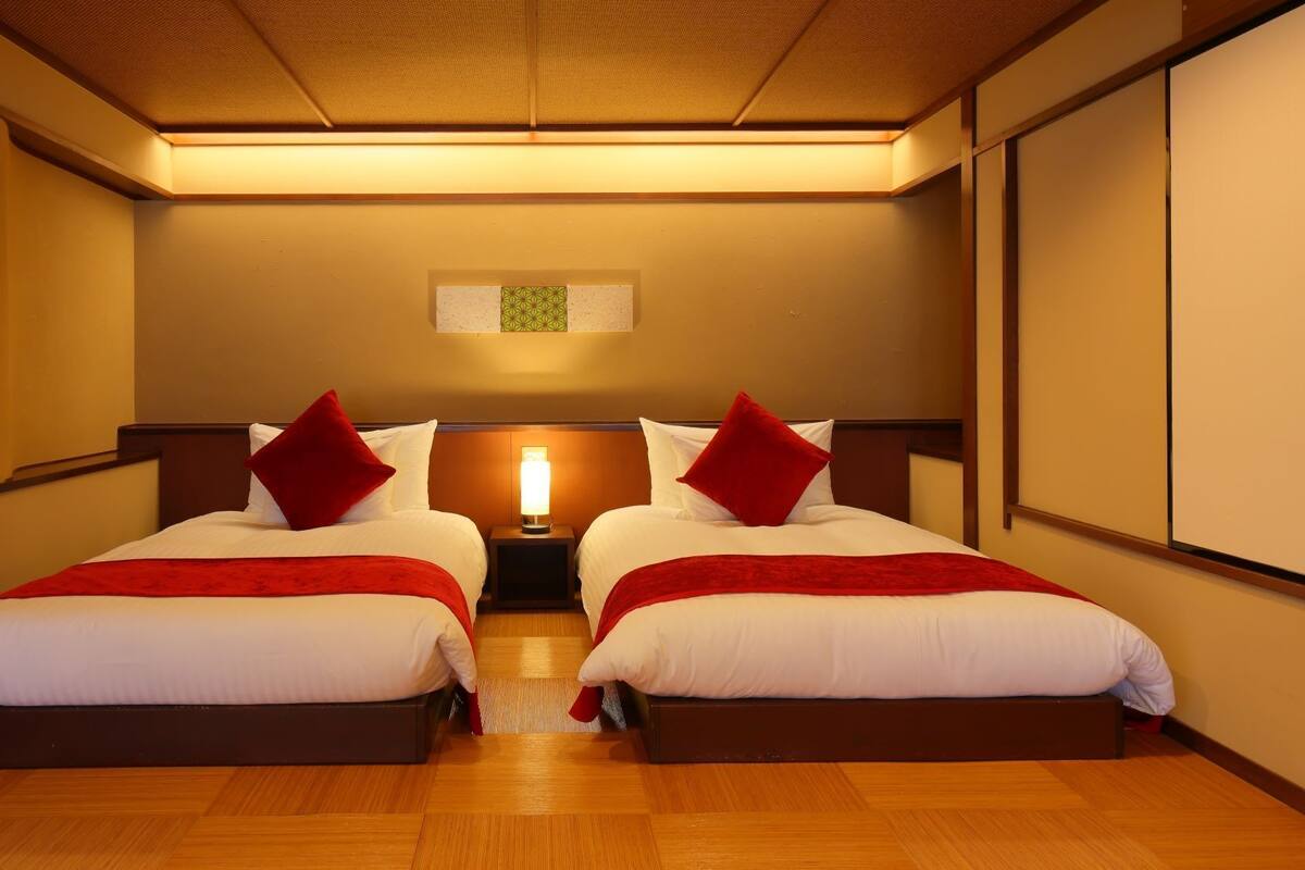 Une chambre d’hôtel avec deux lits, une table de chevet avec une lampe et un luminaire au plafond.