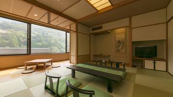 A traditional Japanese room with tatami flooring, a low table, benches, and a television.