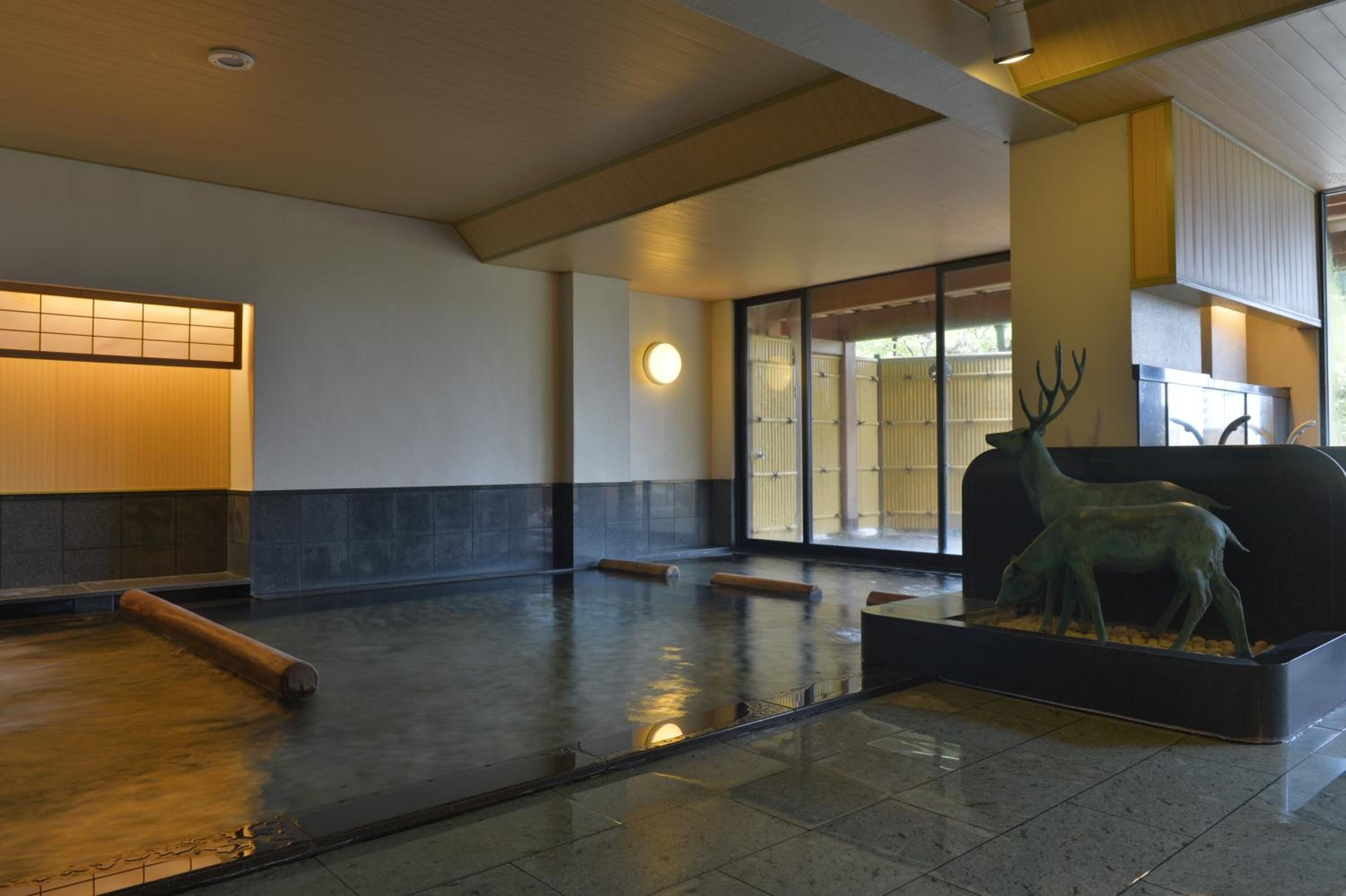 A spacious lobby with a water feature, a deer statue, and traditional Japanese sliding doors.
