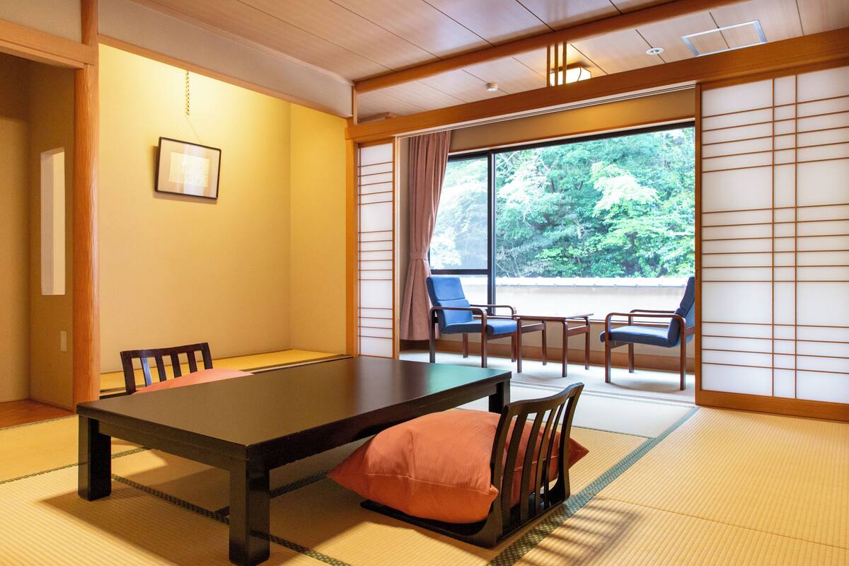 Une pièce de style japonais traditionnel, avec un sol recouvert de tatamis, une table basse et des chaises.