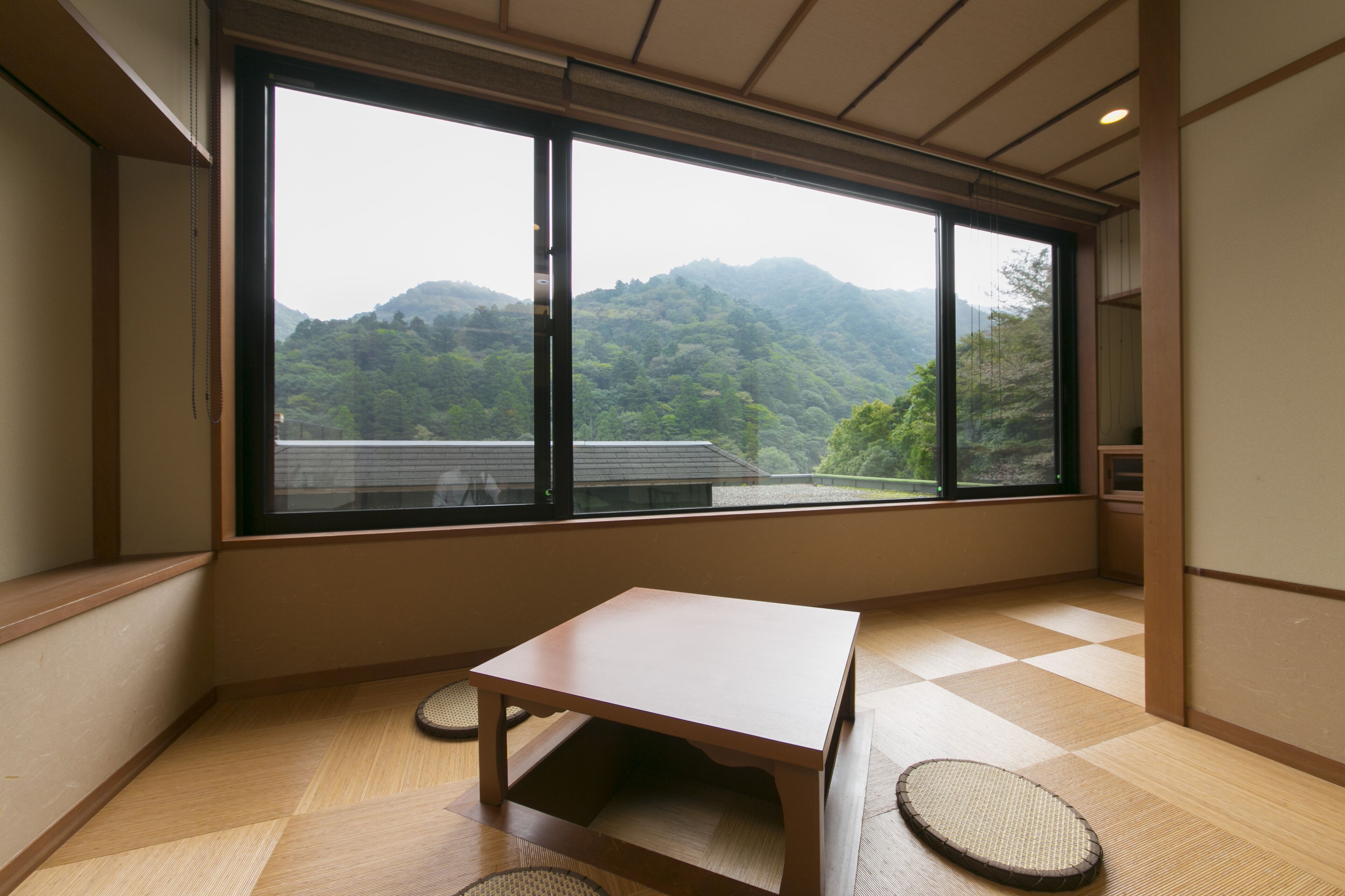 A room with a large window, a small table, and a tatami mat.