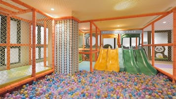 A play area with a ball pit, slides, and safety netting.