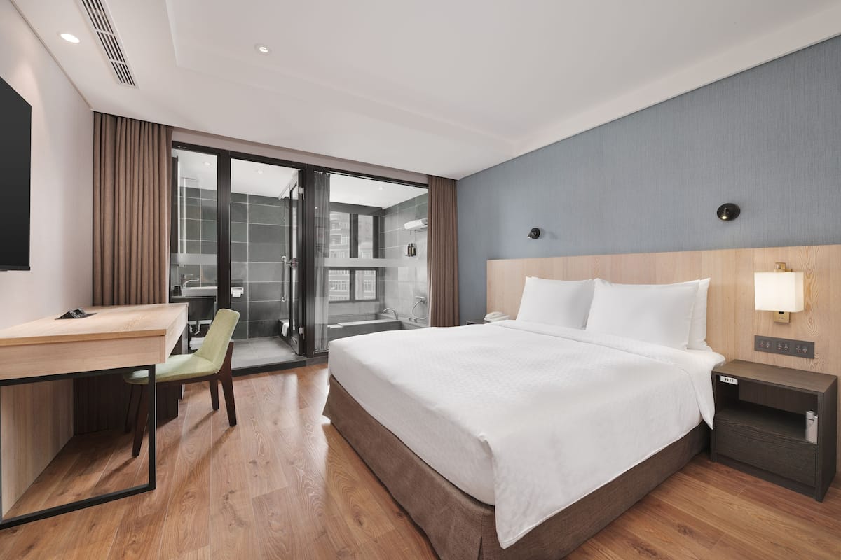 Quarto de hotel moderno com uma cama grande, uma escrivaninha e uma cadeira.