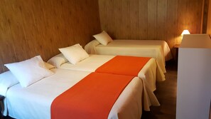 Habitación de hotel con dos camas, cada una con ropa blanca y almohadones naranjas.