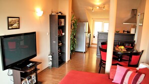 Un soggiorno moderno con una TV a schermo piatto, un divano rosso e un'area pranzo con sedie rosse.