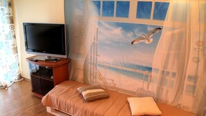 Una camera da letto con un letto, una televisione e una finestra che mostra una spiaggia.