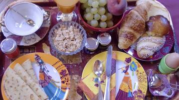Ett frukostbricka med olika sorters mat och dryck, inklusive croissanter, vindruvor och ett glas apelsinjuice.