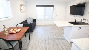 A modern kitchen with a dining table, a sofa, and a TV mounted on the wall. - Port Lincoln Villas (Port Lincoln)