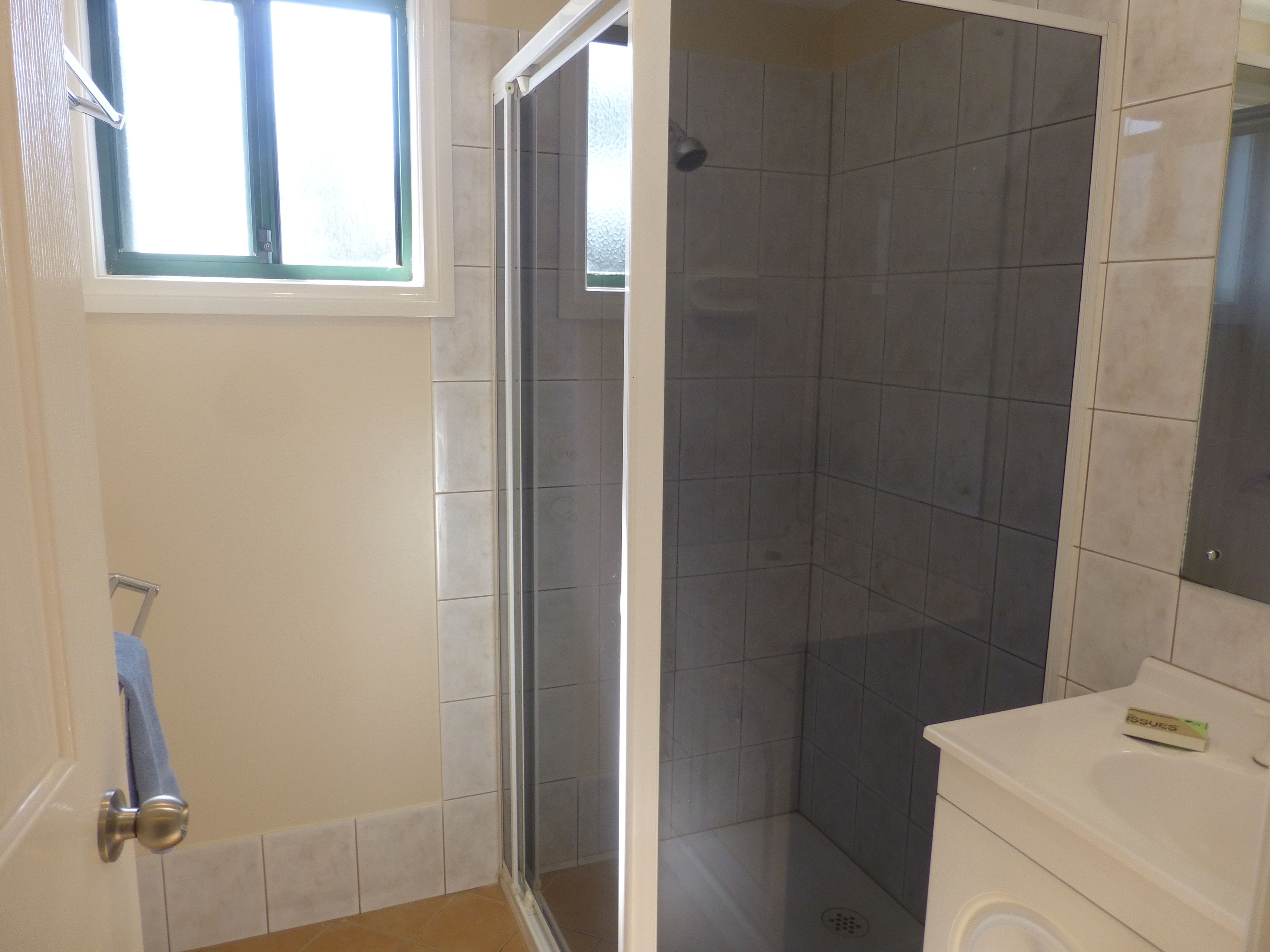 Ein Badezimmer mit Dusche, Toilette und Fenster.