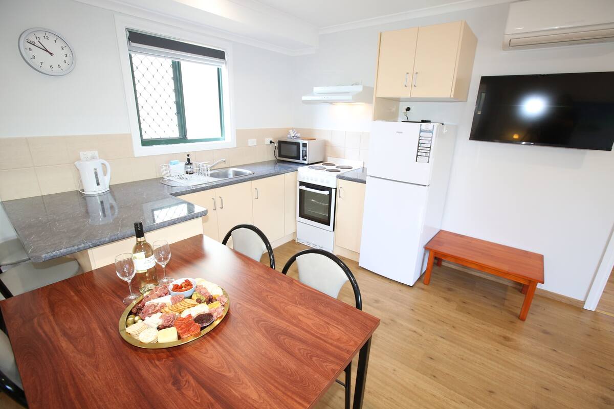 Una cocina moderna con una mesa de comedor de madera, una botella de vino y una tabla de embutidos.