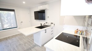 A modern kitchen with a built-in stove, white cabinetry, and a window with a view. - Port Lincoln Villas (Port Lincoln)