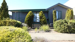 A residential house with a green roof, a large window, and a well-maintained garden with various shrubs and flowers. - Port Lincoln Villas (Port Lincoln)