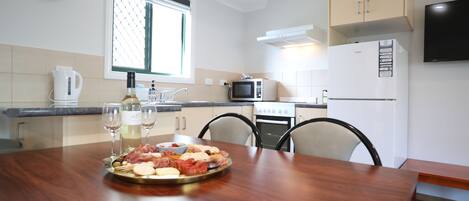 Une cuisine moderne avec une table à manger en bois, une horloge et une fenêtre avec des stores.