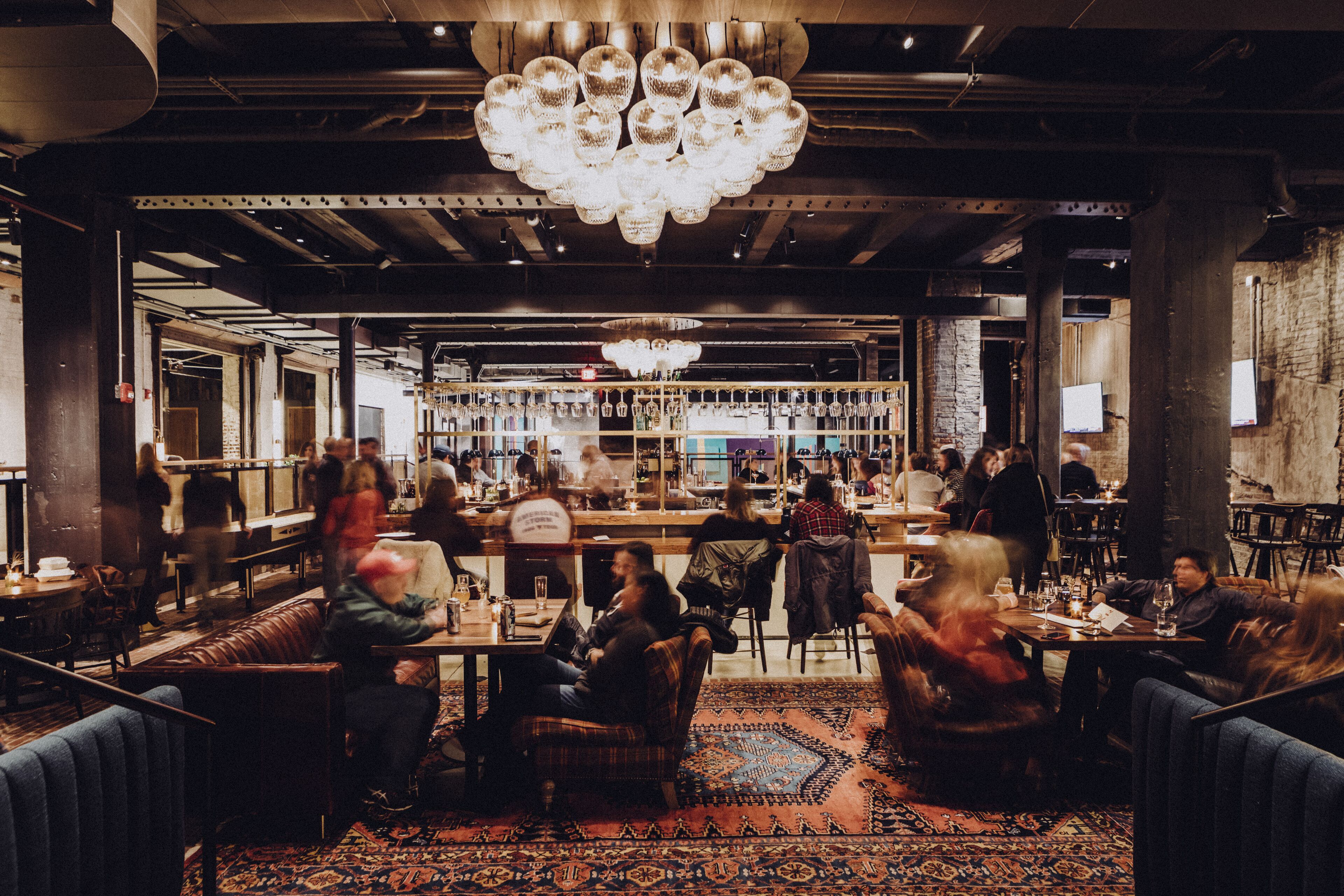 Een restaurant met een bar, zitplaatsen en een kroonluchter.