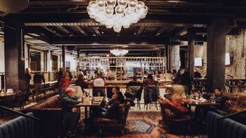 Een restaurant met een bar, zitplaatsen en een kroonluchter.