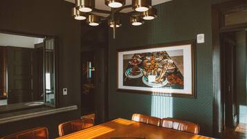 A dining area with a wooden table, leather chairs, a framed picture on the wall, and a ceiling light fixture.