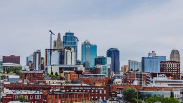 A city skyline with a mix of modern and older buildings, including a prominent blue skyscraper and a construction crane.