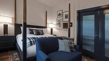 Ein modernes Hotelzimmer mit einem großen Bett, einer Sitzecke und einer Tür mit satinierten Glasfeldern.