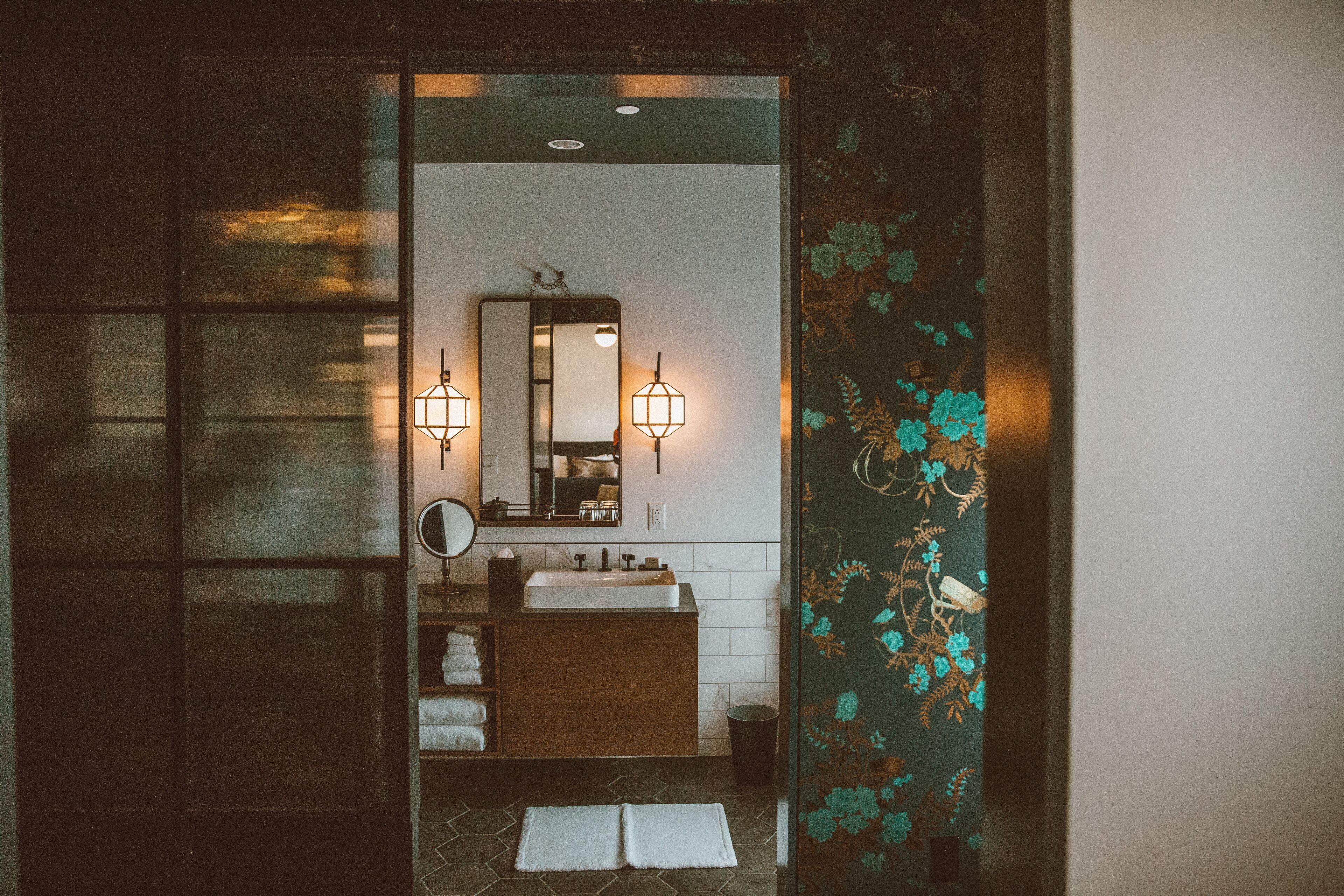 A bathroom with a wooden vanity, a mirror, two wall-mounted lights, and a tiled floor.