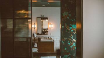 A bathroom with a wooden vanity, a mirror, two wall-mounted lights, and a tiled floor.