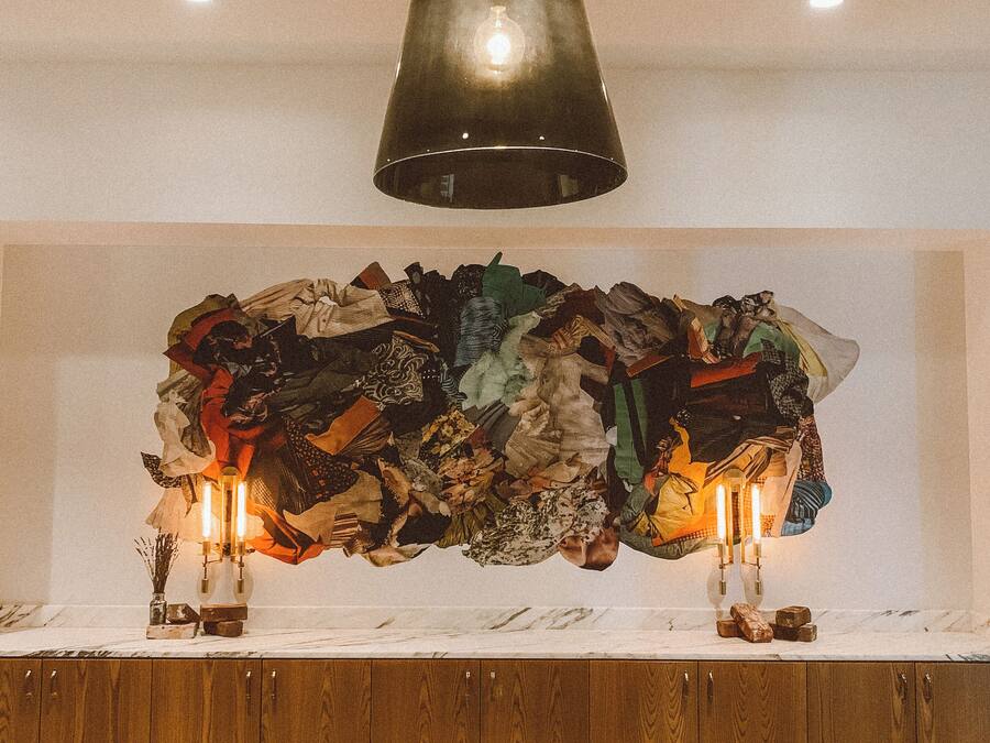 Una habitación con un armario de madera, una pieza decorativa grande en la pared y una campana colgante.