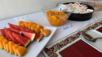 A table with a variety of fruits including watermelon, cantaloupe, and peaches, and a bowl of mixed fruit.