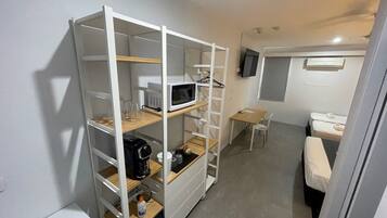 Ett kompakt hotellrum med en inbyggd garderob, ett litet skrivbord, en stol, en säng och en TV som är monterad på väggen.