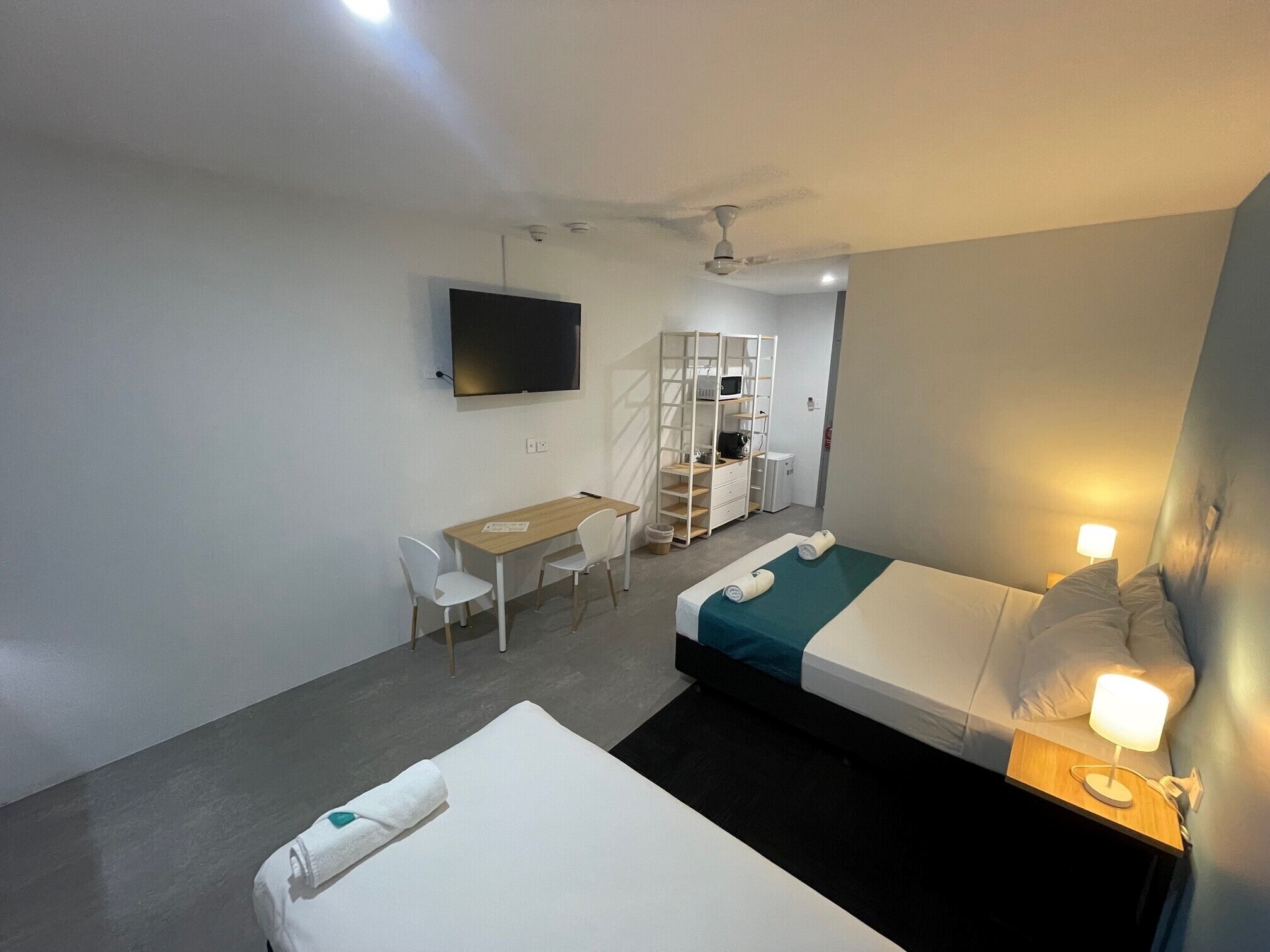 A hotel room with two beds, a desk, a chair, a TV, and a wardrobe.