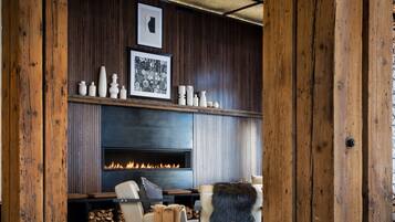 A cozy living room with a fireplace, wooden walls, and a modern sofa.