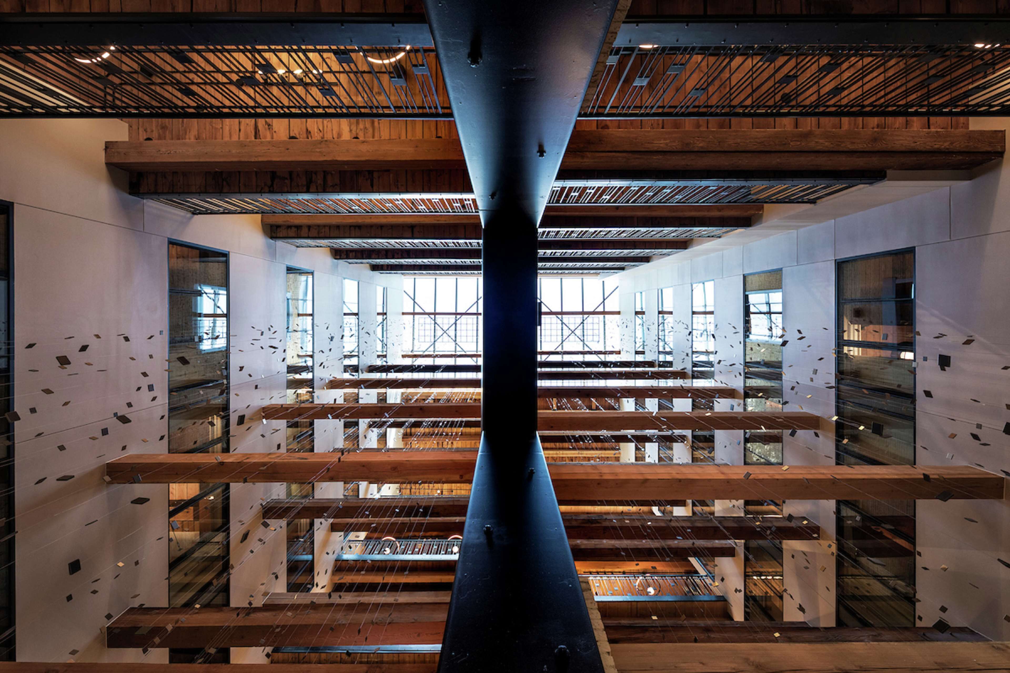 A modern interior with a central column, wooden beams, and large windows allowing natural light.