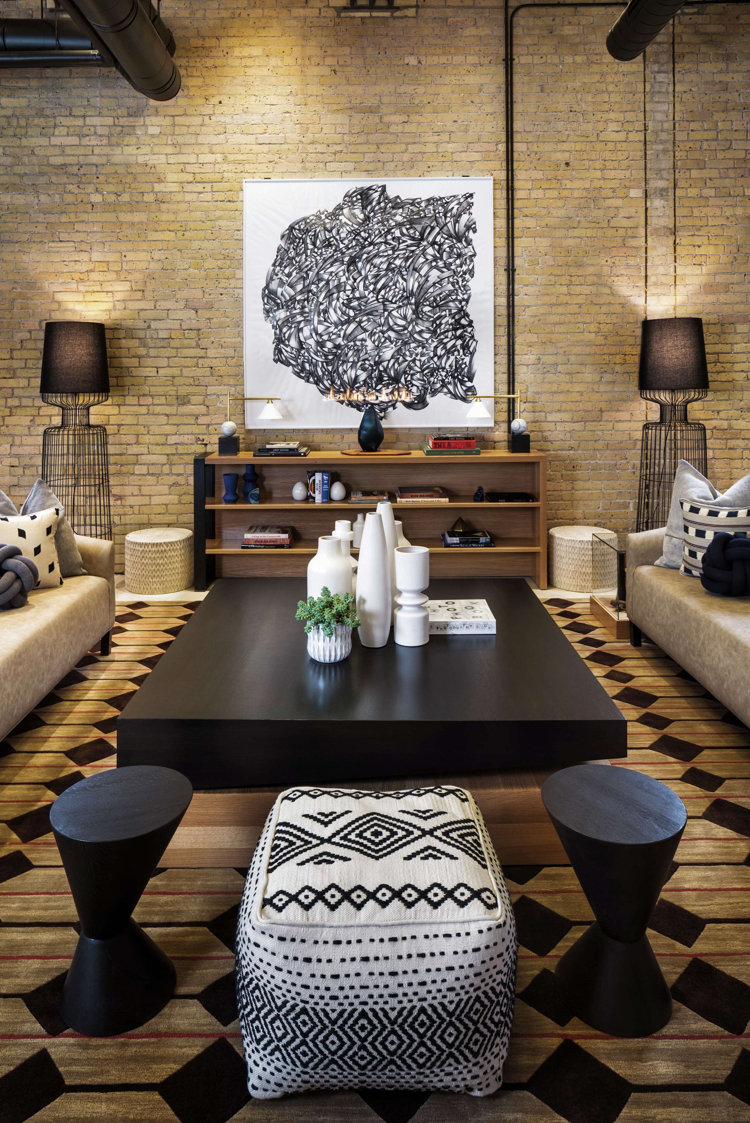 Ein modernes Wohnzimmer mit einem großen abstrakten Gemälde, einem Couchtisch, zwei Sofas und gestreiften Hocker.