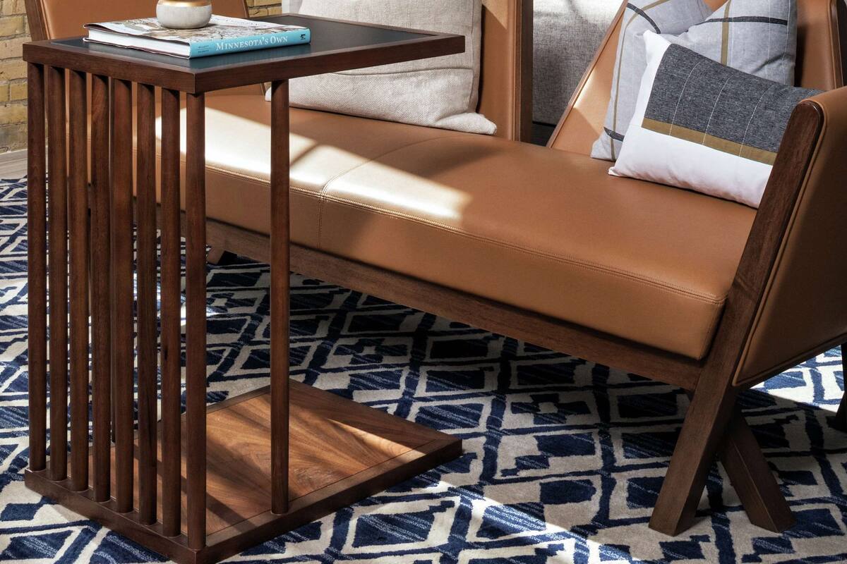 A modern hotel room with a leather sofa, a wooden coffee table, and a patterned rug.